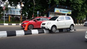 Berkendara Sembari Mainkan Ponsel, Pengemudi Mobil KIA Tabrak Tengah Trotoar Jalan